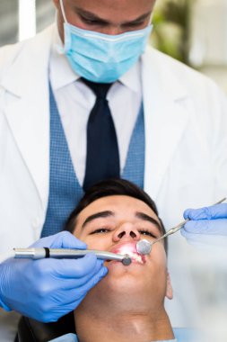 Genç ve çekici bir adam diş tedavisi görüyor. Yakın çekim..
