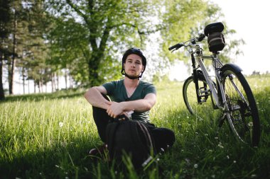 Erkek dağ bisikletçinin çimenlerin üzerinde dinlenme. Bireysel spor, motivasyon, ilham Tema.