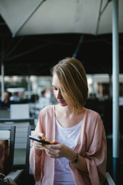 Kafede cep telefonu kullanan genç bir kadın.