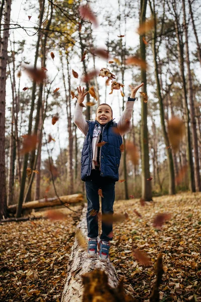 Sevimli ve mutlu küçük çocuk sonbahar parkında eğleniyor ve oynuyor..