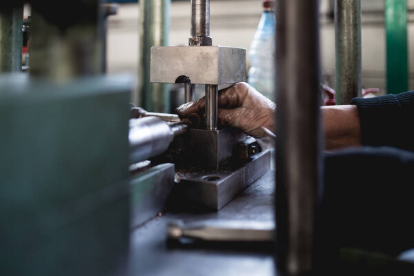 Metallurgy heavy industry. Factory for production of heavy pellet stoves and boilers. Worker hands close up. Extremely dark conditions and visible noise.