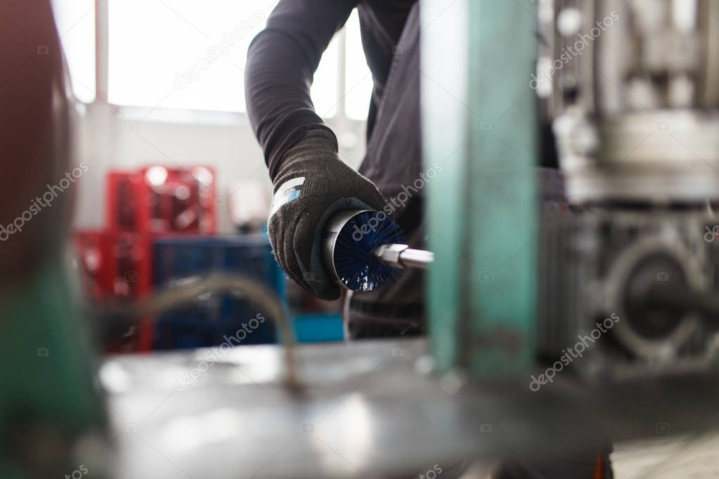 Metallurgy heavy industry. Factory for production of heavy pellet stoves and boilers. Worker hands close up. Extremely dark conditions and visible noise.