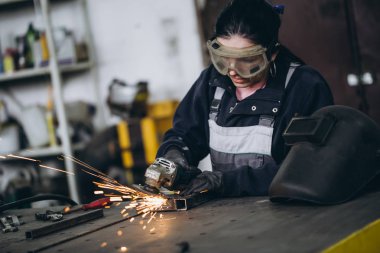 Güçlü ve değerli bir kadın araba ve motosiklet tamircisi zor iş yapıyor. O değirmeni bazı metal bisiklet parçaları düzeltmek için kullanma. 