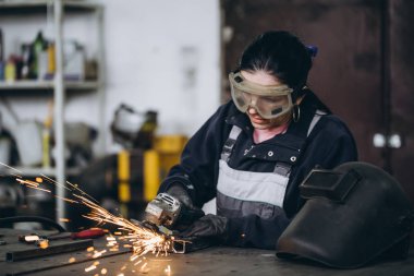 Güçlü ve değerli bir kadın araba ve motosiklet tamircisi zor iş yapıyor. O değirmeni bazı metal bisiklet parçaları düzeltmek için kullanma. 