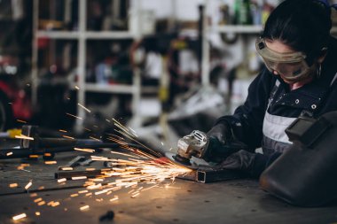 Güçlü ve değerli bir kadın araba ve motosiklet tamircisi zor iş yapıyor. O değirmeni bazı metal bisiklet parçaları düzeltmek için kullanma. 