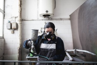 Güçlü ve değerli kadın zor iş yapıyor. Bazı metal ürünler boyama için endüstriyel sprey kompresör kullanıyor. 