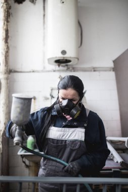 Güçlü ve değerli kadın zor iş yapıyor. Bazı metal ürünler boyama için endüstriyel sprey kompresör kullanıyor. 