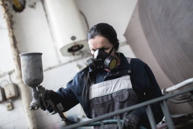 Güçlü ve değerli kadın zor iş yapıyor. Bazı metal ürünler boyama için endüstriyel sprey kompresör kullanıyor. 