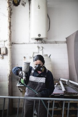 Güçlü ve değerli kadın zor iş yapıyor. Bazı metal ürünler boyama için endüstriyel sprey kompresör kullanıyor. 