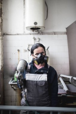 Güçlü ve değerli kadın zor iş yapıyor. Bazı metal ürünler boyama için endüstriyel sprey kompresör kullanıyor. 