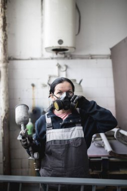 Güçlü ve değerli kadın zor iş yapıyor. Bazı metal ürünler boyama için endüstriyel sprey kompresör kullanıyor. 