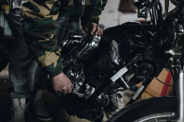 Strong and worthy man doing hard job in car and motorcycle repair shop.