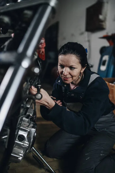 Strong and worthy woman doing hard job in car and motorcycle repair shop.