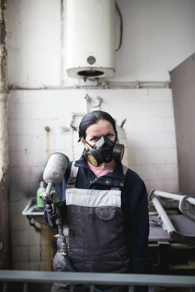 坚强而有价值的女人做艰苦的工作 她用工业喷雾压缩机涂一些金属制品 — 图库照片