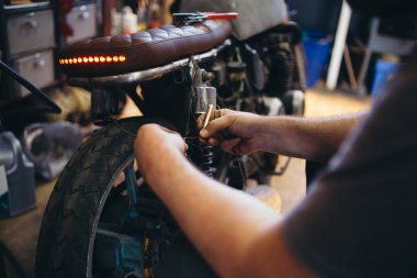 Özel yapılmış motosiklet atölyede çalışan deneyimli adam görüntüsünü kapatmak. 