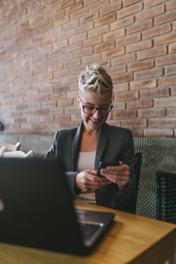Modern ofisinde çalışan gözlüklü genç pozitif kadın. 