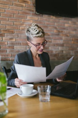 Modern ofisinde çalışan gözlüklü genç pozitif kadın. 