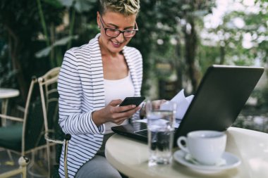 Güzel bahçe cafe bar veya restoran gibi oturan ve onun dizüstü bilgisayarda bir şeyler yapıyor genç mutlu kadın.