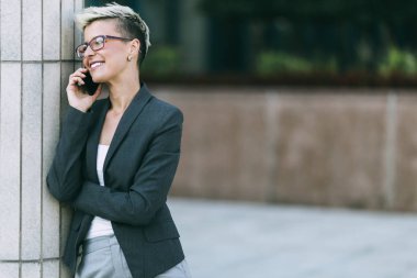 Cep telefonu kullanarak büyük modern binanın önünde genç iş kadını.