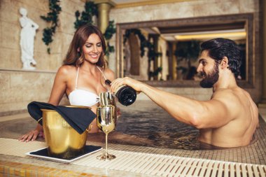 Zevk ve Spa merkezinde rahatlatıcı güzel genç bir çift. Jakuzide oturma ve şarap içme.