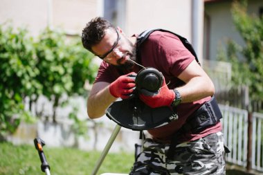 Sakal ile Orta yaşlı adam ev bahçesinde veya bahçede çim düzeltici ile çalışan