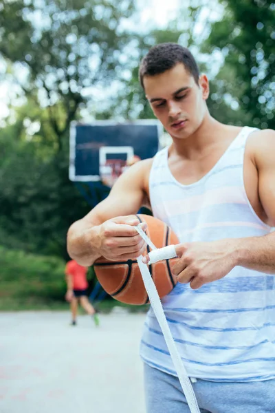 Young athletic man fixing injury on basketball court