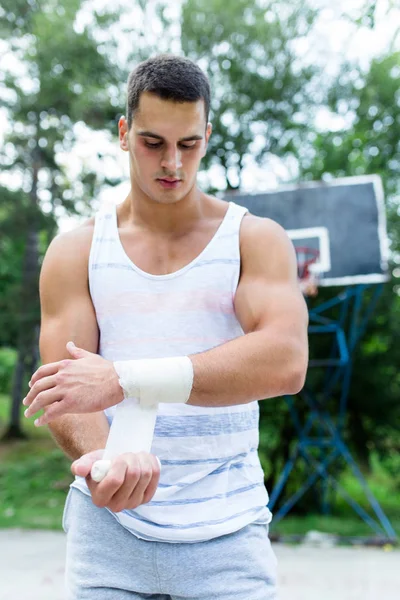 Young athletic man fixing injury on basketball court