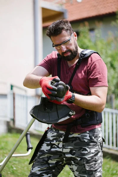 中年男子与胡子工作与草修剪器在家庭庭院或花园 — 图库照片