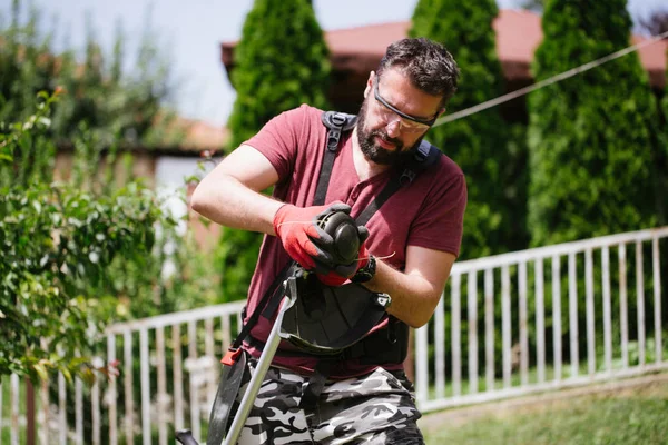家の庭や庭で草トリマーで働くひげを持つ中年の男性 — ストック写真
