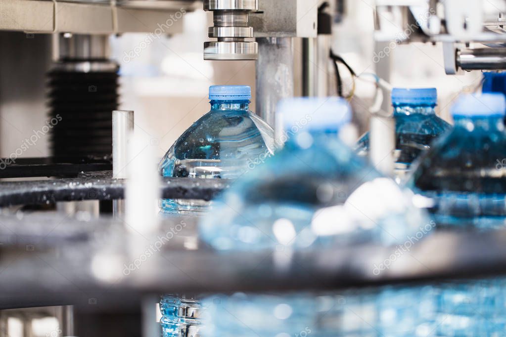 Industrial factory indoors and machinery. Robotic factory line for processing and bottling of pure spring water into canisters and bottles