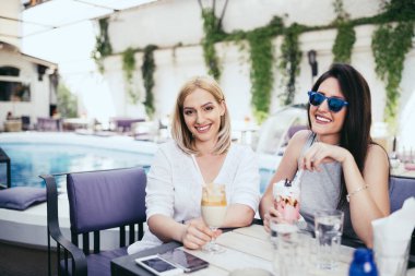 İki genç ve güzel kadın özel kokteyl evi partide zevk. Gülümsüyorlar ve kameraya bakıyorlar. Arka planda yüzme havuzu.