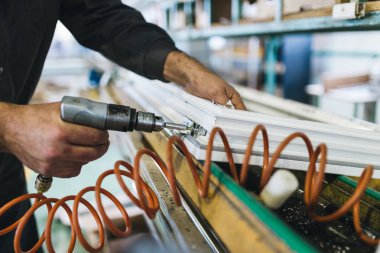 Alüminyum ve PVC profilleri kesen el işi işçisi. İmalat işleri. Seçici odaklanma. Alüminyum ve PVC pencere ve kapı üretim fabrikası.