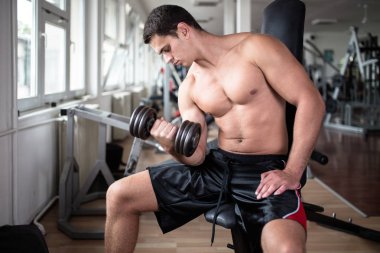 Egzersiz ve fitness spor salonunda ağırlık kaldırma işi genç çekici yetişkin bir adam. Kapalı eğitim spor.