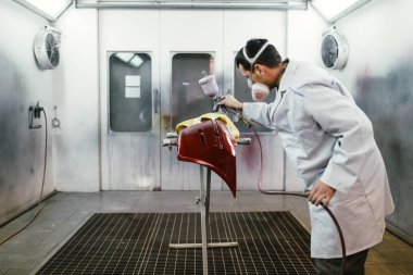 Koruyucu giysi ve araba parçaları sprey Kompresör kullanarak boyama maskesi olan adam. Seçici odak. 