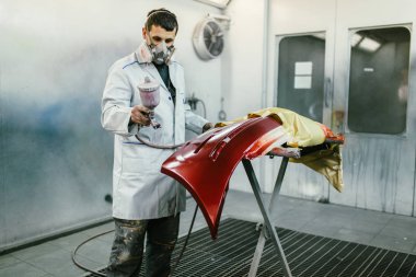 Koruyucu giysi ve araba parçaları sprey Kompresör kullanarak boyama maskesi olan adam. Seçici odak. 