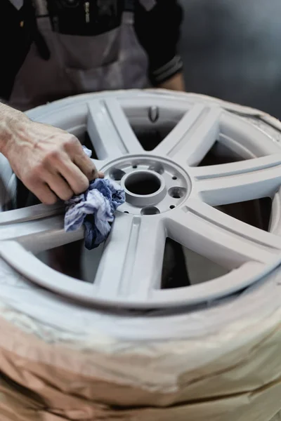 Man with protective clothes painting car parts using spray compressor. Selective focus.