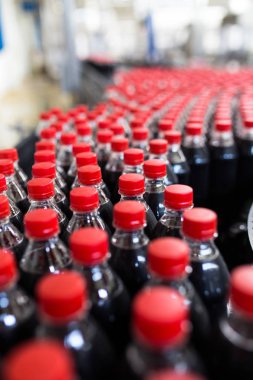 Şişeleme fabrikası - siyah meyve suyu veya meşrubat işleme ve şişe suyu şişeleme için satır şişeleme. Seçici odak. 