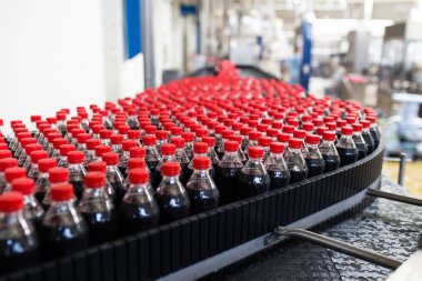 Şişeleme fabrikası - siyah meyve suyu veya meşrubat işleme ve şişe suyu şişeleme için satır şişeleme. Seçici odak. 