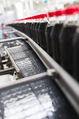 Şişeleme fabrikası - siyah meyve suyu veya meşrubat işleme ve şişe suyu şişeleme için satır şişeleme. Seçici odak. 