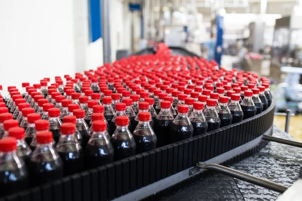 Bottling factory - Black juice or soft drink bottling line for processing and bottling juice into bottles. Selective focus.