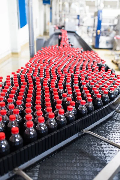 Bottling factory - Black juice or soft drink bottling line for processing and bottling juice into bottles. Selective focus.