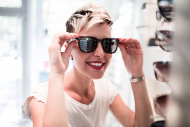 Güzel orta yaşlı kadın gözlükçüden gözlük seçiyor..
