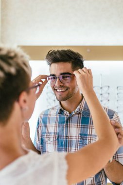 Optik mağaza çekici genç çift gözlük satın alma ve gülümseyerek