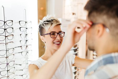 Optik mağaza çekici genç çift gözlük satın alma ve gülümseyerek