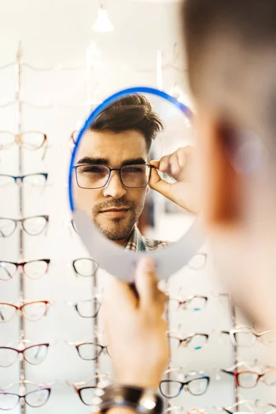 Yakışıklı Genç Adam Gözlük Çerçevesini Optik Mağazada Seçiyor — Stok fotoğraf