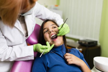 Sevimli küçük okul kız diş tedavisi sırasında diş sandalyesinde oturan. Yakın çekim. Seçici odak. Diş sağlığı kavramı.