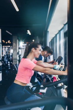 Spor salonunda bisiklet süren genç ve çekici bir kadın ve erkek. Bisiklet sürerken bacak egzersizi ve kardiyo egzersizi yapıyorlar..