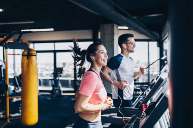 Modern spor salonunda koşu bandında koşan genç erkek ve kadın..