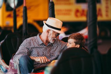 Büyükbaba ve torunu eğlenmek ve eğlence parkında birlikte iyi kaliteli zaman harcamak. Onlar zevk ve birlikte tampon araba sürerken gülümseyen.