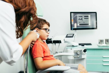 Tıbbi muayenede genç çocuk veya otolaryngologist ofisinde kontrol. Kulak sulama ve kulak kiri kaldırma. 
